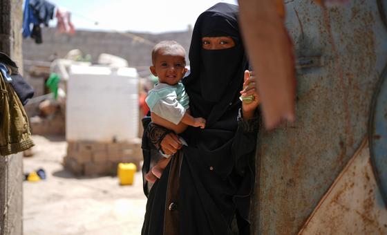 أم تحمل طفلها بالقرب من منزلهما في حي العدني بمدينة الحوطة في اليمن.